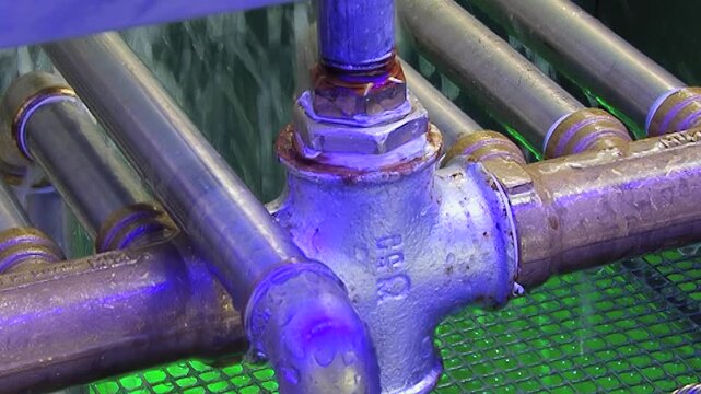 Observe a dynamic hydro air filter in action. Glistening metal pipes and robust valves guide the water flow, illuminated by an ethereal blue light.