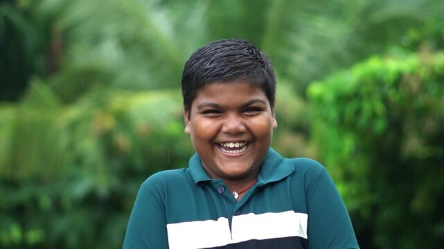 Happy Indian Boy Laughing Out Loud Looking At Camera Outdoors Front View. Excited Young Indian Child Laughing Expressively Outdoors.