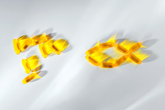 Golden omega 3 fish oil capsules arranged in the shape of a fish on white background, symbolizing dietary supplements, vitamins and healthy nutrition for well being