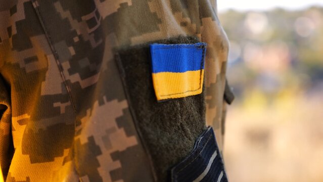 Close up of military blue-yellow chevron on shoulder of soldier at countryside. This emblem embodies the unbreakable spirit and pride of the ukrainian people. Concept of invasion resistance