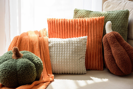 Autumnal Arrangement of Plush Pumpkins and Textured Throw Pillows on Sofa Cozy Home Decor
