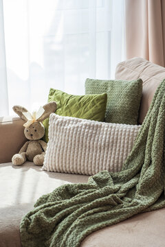 Comfortable sofa arrangement with plush pillows and a knitted bunny toy creating cozy home atmosphere