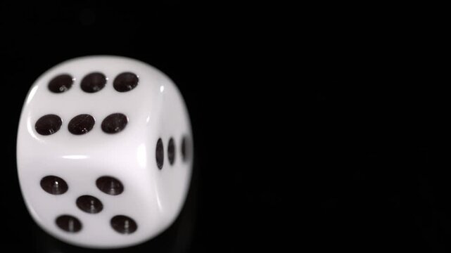Slow motion capture of a die rolling across a black surface with detailed movement analysis