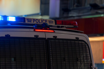 Illuminated blue emergency strobe beacon mounted on an urban police vehicle during a nighttime security patrol. © Sergej