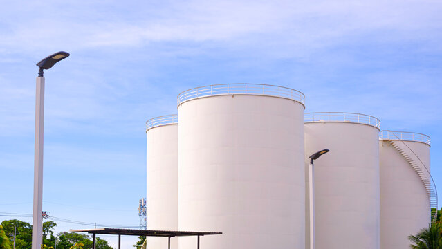 Group of storage fuel crude oil tanks in petroleum industrial refinery area against blue sky background