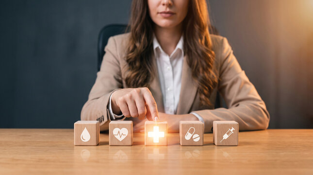 Professional woman arranging wooden blocks with healthcare icons on a desk for World Patient Safety Day concept