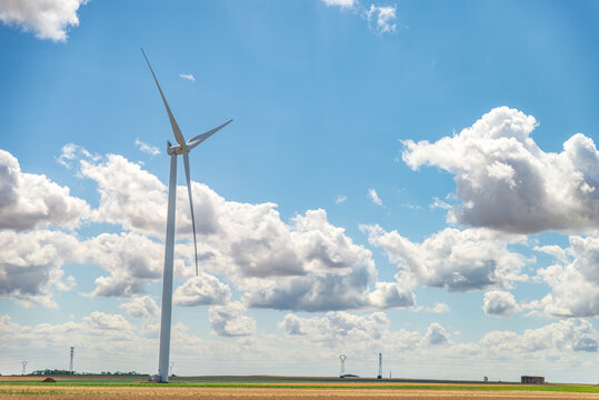 &Eacute;olienne solitaire dans un champ agricole sous un ciel bleu d'&eacute;t&eacute; nuageux