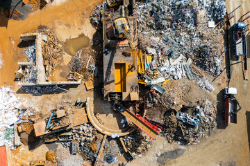 Fototapeta premium Aerial view of large metal scrap piles and heavy excavators at a industrial recycling facility