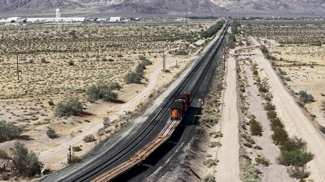 Aerial View of Locomotive and Flatcars Traversing Arid Desert, Camera Rising and Pulling Away