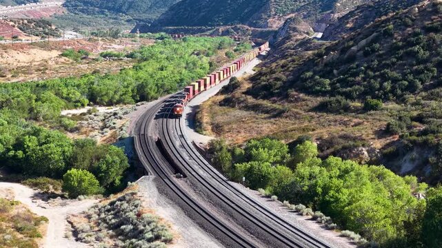 High-Angle View of Long Freight Train Winding Through Mountain Valley