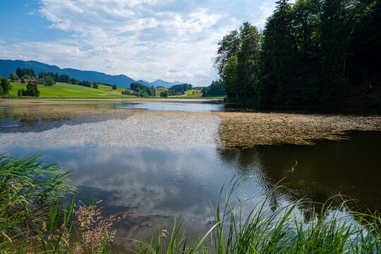 Idyllischer Biberschw&ouml;ller See mit Wolkenspiegelung und Voralpenkulisse.