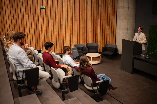 Young speaker presenting to audience in modern lecture hall
