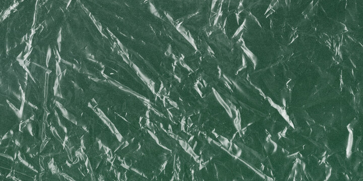 Crumpled green foil texture background, metallic emerald paper with creased surface, shiny wrinkled foil wrap for holiday gift packaging