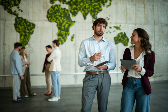 Business people discussing sustainability in modern office with global map