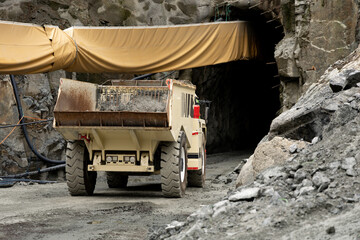 Heavy-duty dump truck positioned at the entrance of a mining tunnel, surrounded by rocky terrain and construction materials, showcasing industrial machinery in action © Kateryna Muzhevska