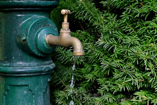 Dripping water from an old brass faucet as a concept for saving water