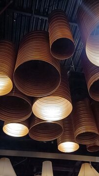 Vertical low angle shot of modern industrial ceiling lamps made of bronze corrugated pipes. Stylish lighting installation in loft interior design.