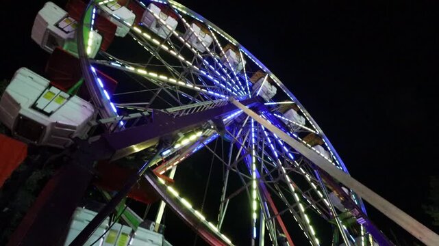 Wide angle lens looking up at a ferris wheel at night with all the lights turned on as it spins.