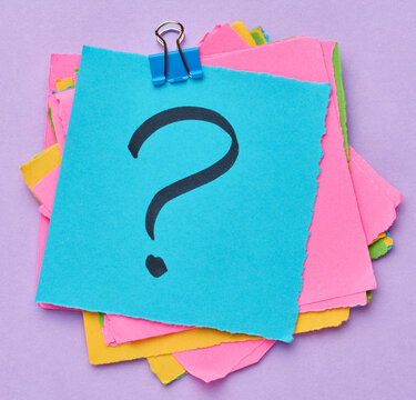 A stack of multi-colored square sticky notes with a question mark on them, concept of finding a solution and making a choice