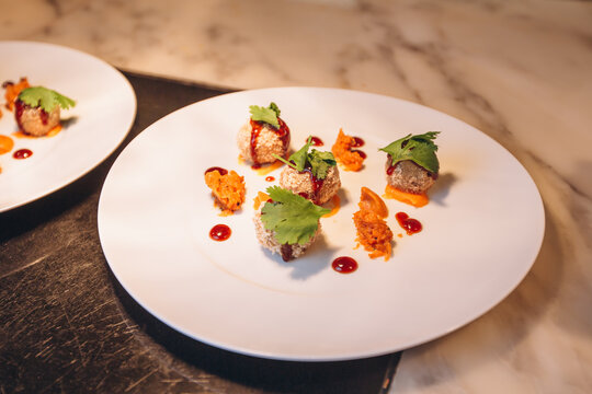 Gourmet Appetizer Presentation: Delicate, bite-sized appetizers artfully arranged on a white plate, drizzled with sauce and garnished with fresh herbs, showcasing culinary artistry.