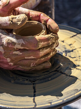 Potter Shaping Clay on a Spinning Wheel, Hands-On Pottery Making at an Outdoor Workshop