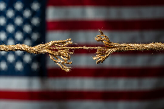 Fraying rope on American flag background closeup. Frayed sisal rope about to break on USA flag background. Metaphor for American political division, economic crisis, social tension, broken relations