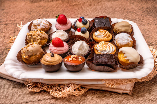 Assortment of miniature pastries and bite-sized desserts with chocolate, cream, berries, caramel, nuts and fruit arranged on a serving tray