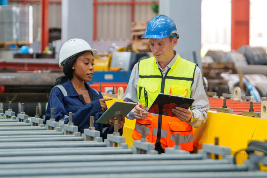 Engineers Collaborating in a Manufacturing Facility, Reviewing Project Documents for Effective Team Management