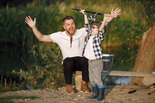 Young father teaching his little toddler son how to fish