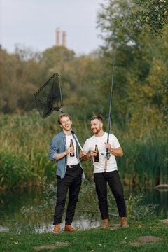 Two men fishing near the river and drinking a beer