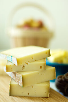 Thick slices of Fontina cheese in a styled pile with other ingredients in a blurred background
