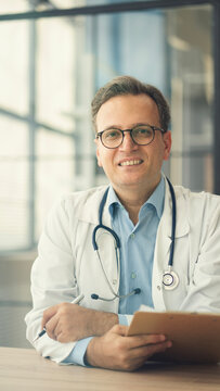 Portrait of male doctor sitting at desk in office clinic