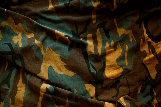 Full-frame texture of rumpled camouflage fabric featuring classic military green, brown, and tan tones.