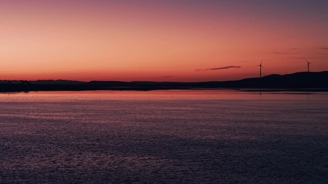 Tranquil wide shot of a serene lake horizon at dawn twilight with orange afterglow. Ideal for cinematic b-roll, mindfulness backgrounds, and nature documentary intros.