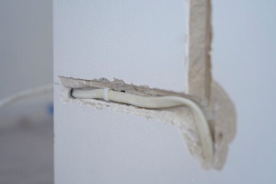 Electrical cable placed inside channel cut into interior wall. Cable installation and home wiring