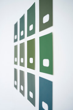 Green paint samples in different shades arranged on white wall for comparison