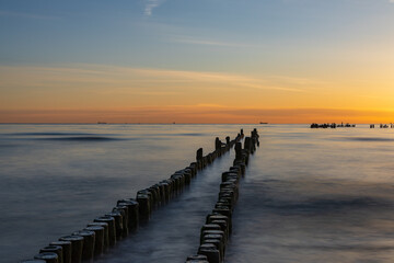 Obraz premium Deep Perspective Long Exposure Landscape Of Breakwater Piles In Calm Ocean