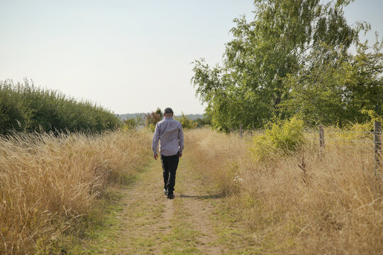 Person walking in a field of sun dried grass 
