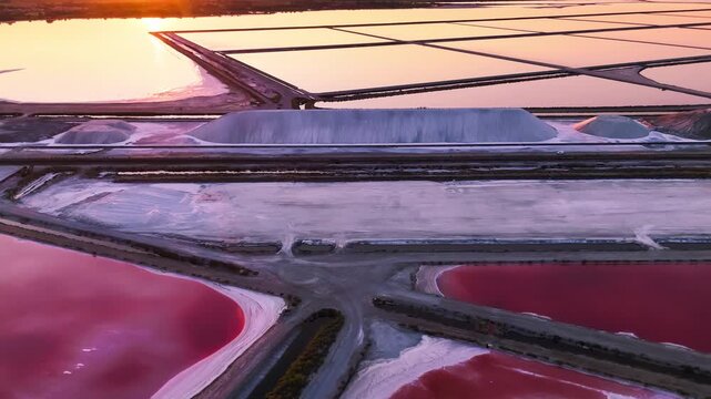 Aerial drone view of pink lakes salt marshes, salt mining medieval town of Aigues-Morte, Camargue, France. High quality 4k footage
