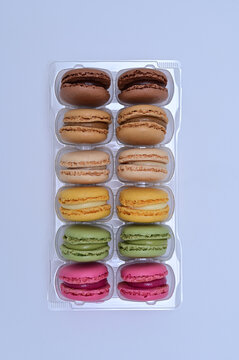 Vertical top view of rows of colorful french macarons in plastic tray