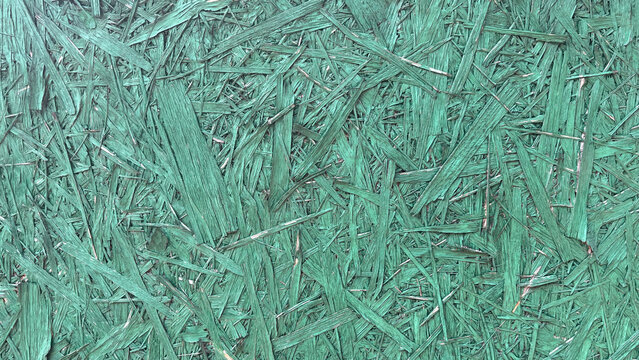 Close‑up of green OSB (oriented strand board) panel showing compressed wood strands and layered engineered texture, creating a distinctive construction material background with geometric patterns.