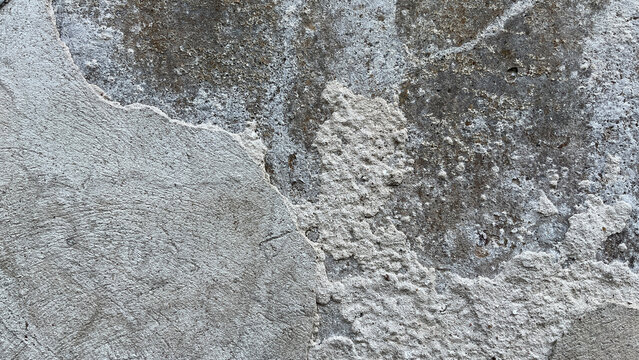 Close‑up of a weathered wall with layers of deteriorating plaster and exposed rough substrate, creating an abstract architectural texture with contrasting surfaces, erosion, and aged character.