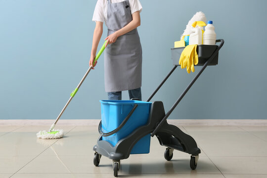 Professional cleaning service and hygiene, person mopping floor with cleaning supplies and bucket on a cart