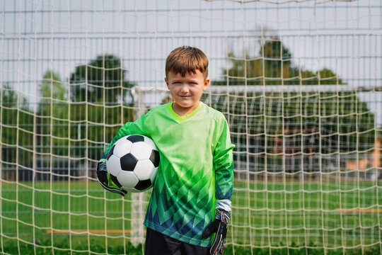 A cute boy as a goalkeeper in the soccer goal. Successful youth soccer training.