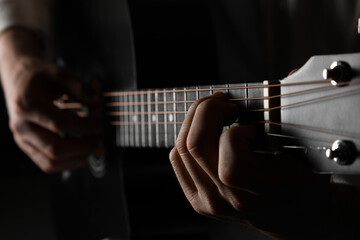 Fototapeta premium Music education and creative expression, hands playing acoustic guitar strings in a dark, moody setting