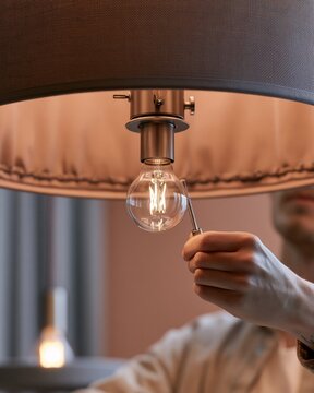 Person Repairing a Light Bulb in a Lamp Shade with Threaded Rod Detail