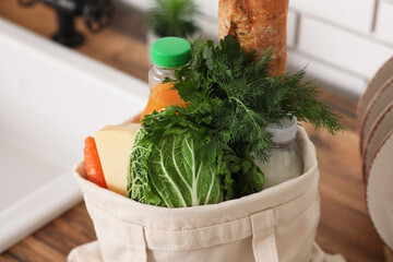 Shopping bag with different fresh products on counter in kitchen