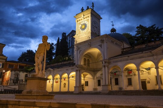 Illuminated main square Piazza della Libert&agrave; with Loggia e Tempietto di San Giovanni and clock tower, Castello di Udine behind, blue hour, dramatic sky, old town, Udine, Friuli-Venezia Giulia, Italy