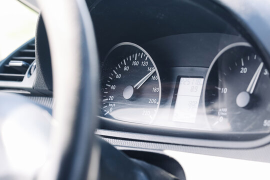 Car dashboard and high speedometer. Instrument cluster behind steering wheel. Speed gauge near highway velocity. Driving safety and speeding concept. Automotive background with dashboard instruments.