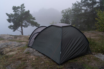 Camping tent pitched on rocky cliff shore in thick morning fog mist at Rummu quarry lake in wild Estonian nature Estonia © Dmitri